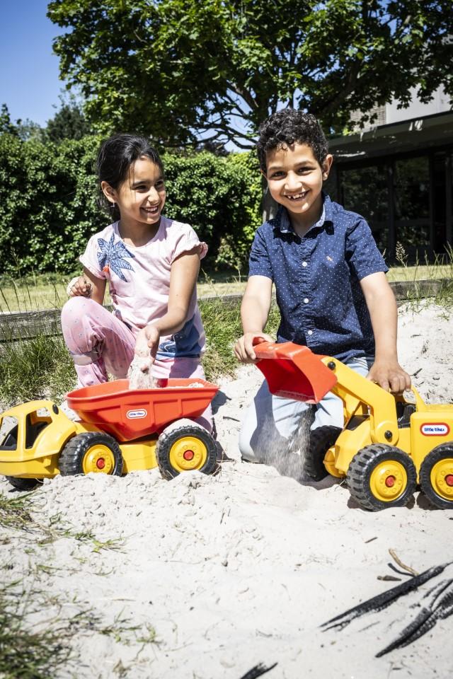 Meisje en jongen spelen met vrachtwagens in zandbak en lachen in De Leerexpert August Leyweg 14